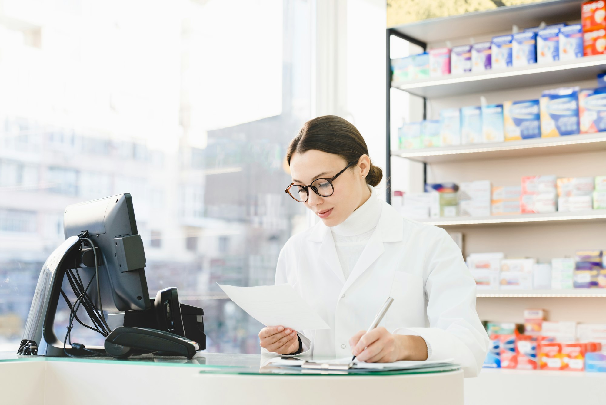 Druggist checking writing information about medicines pills remedies on prescription in pharmacy